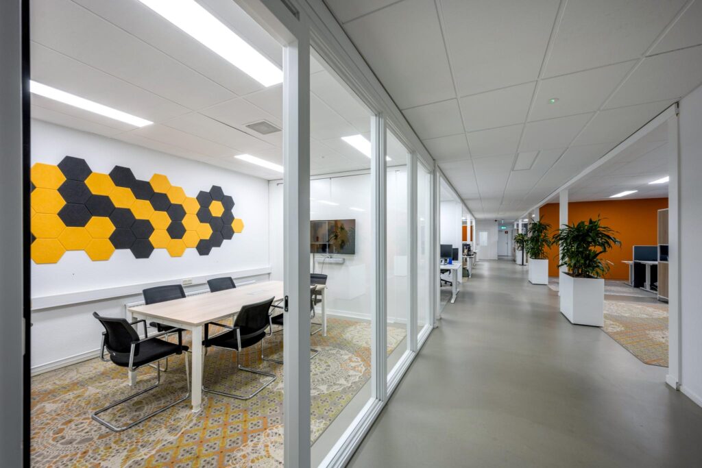 Moderne kantoorruimte aan de Van der Madeweg met glazen vergaderruimte, kleurrijke wanddecoratie en open werkplekken.